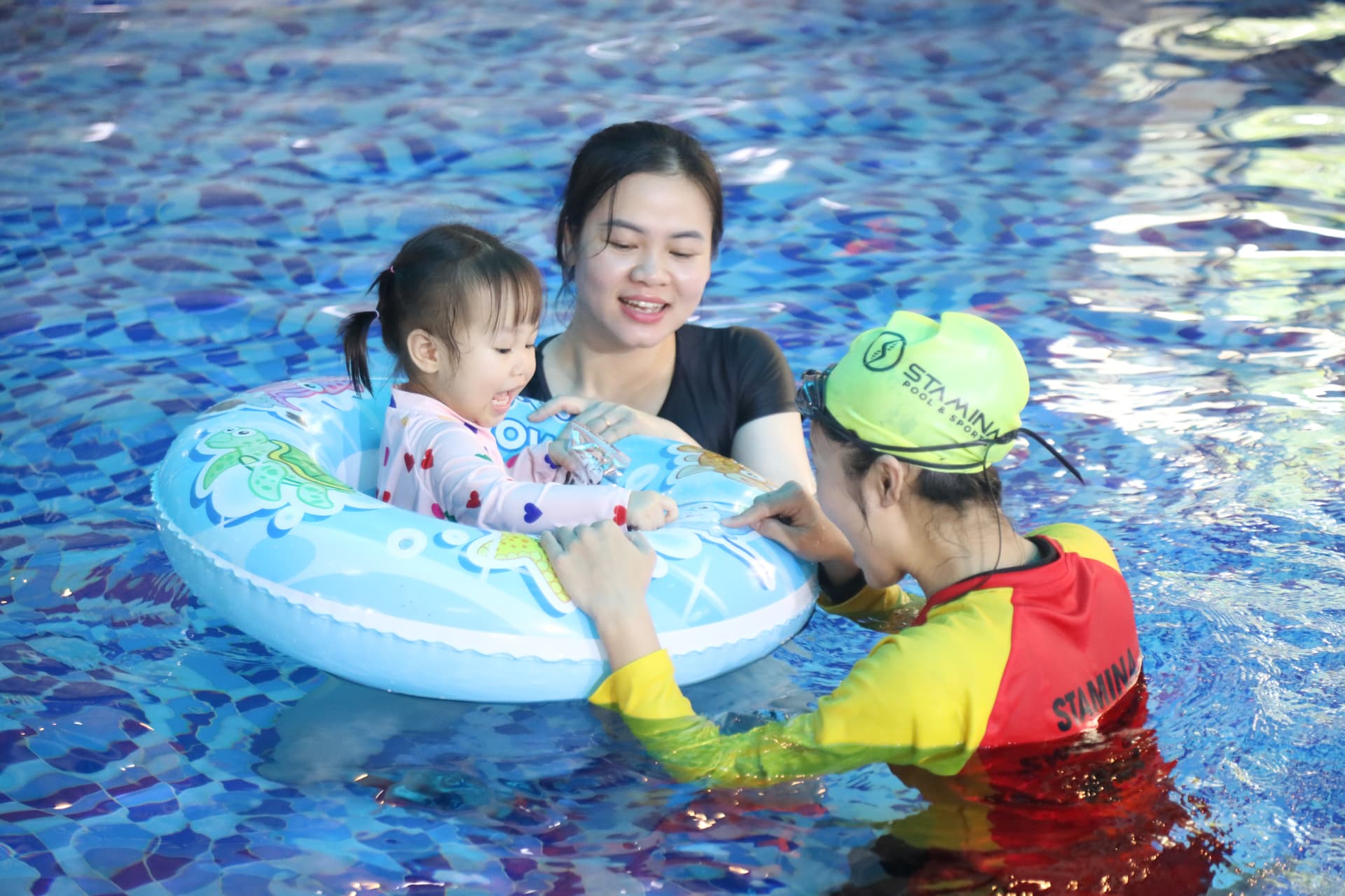Bé làm quen với nước cùng mẹ và giáo viên tại bể bơi trong nhà