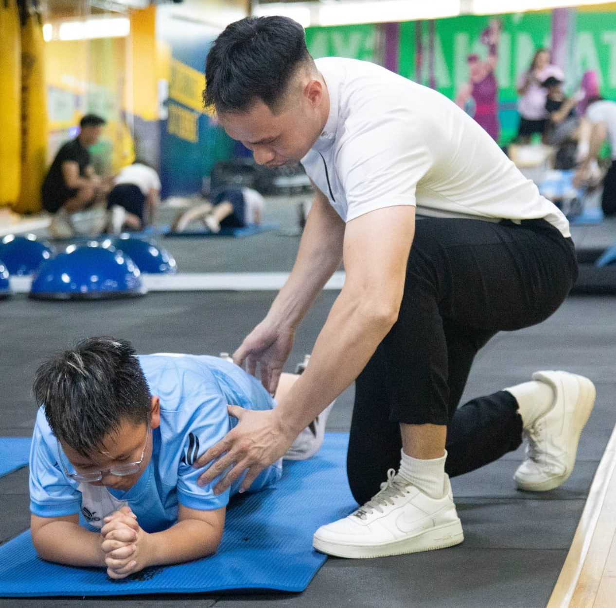 Huấn luyện viên hướng dẫn bé tập plank tại STAMINA Gym Kid